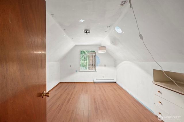 additional living space with a baseboard heating unit, wood finished floors, lofted ceiling, and baseboards