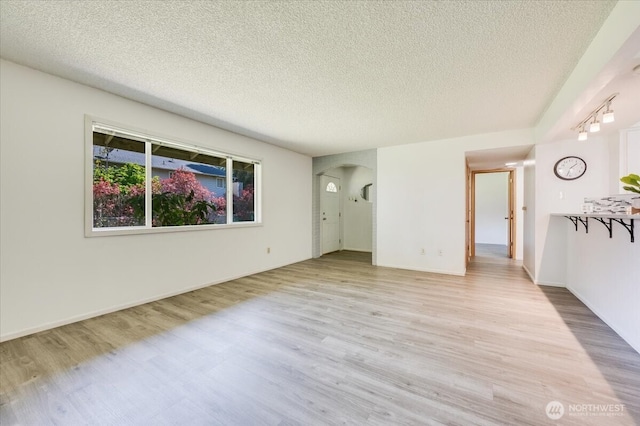 4502 216th St SW Unit A, Mountlake Terrace, WA 98043 - unfurnished living room with arched walkways, a textured ceiling, and light wood-style floors