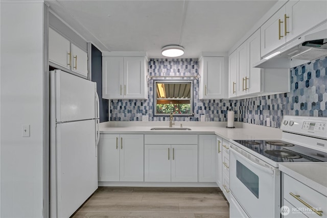 kitchen with white appliances, light countertops, under cabinet range hood, white cabinets, and a sink