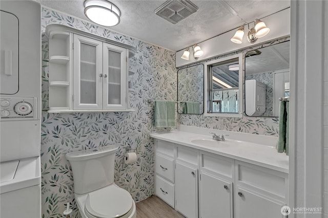 bathroom with toilet, wallpapered walls, and visible vents
