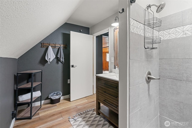 27510 Hwy 97, Cle Elum, WA 98922 - bathroom featuring lofted ceiling, a textured ceiling, a tile shower, vanity, and wood finished floors