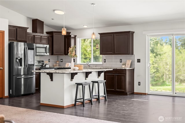 kitchen featuring dark brown cabinets, appliances with stainless steel finishes, decorative backsplash, and a healthy amount of sunlight