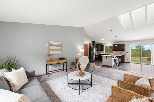 living area featuring baseboards and vaulted ceiling with skylight