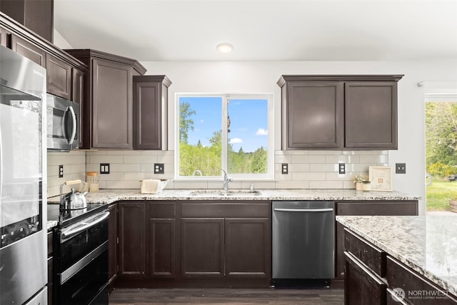 kitchen with a sink, appliances with stainless steel finishes, dark brown cabinets, and tasteful backsplash