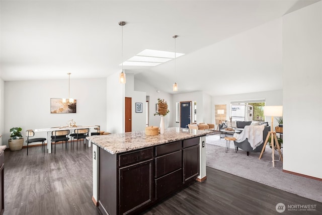 kitchen with pendant lighting, dark wood-style flooring, lofted ceiling, a kitchen island, and light stone countertops
