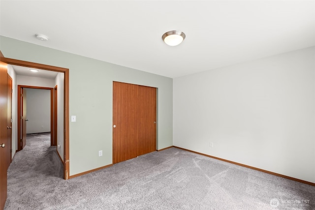 unfurnished bedroom featuring carpet floors, baseboards, and a closet