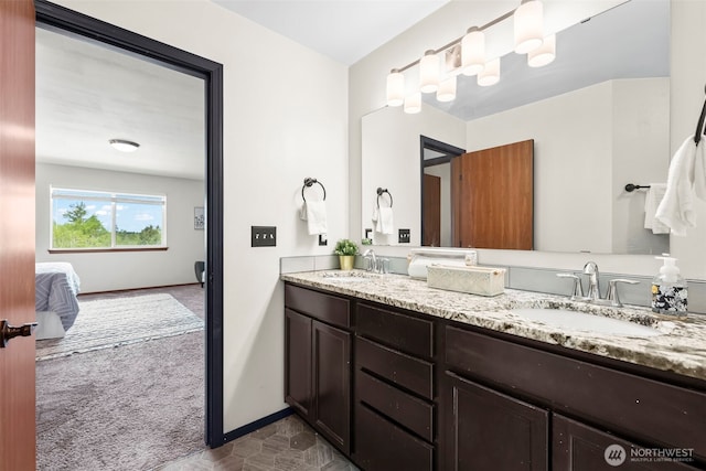 ensuite bathroom with baseboards, a sink, and connected bathroom