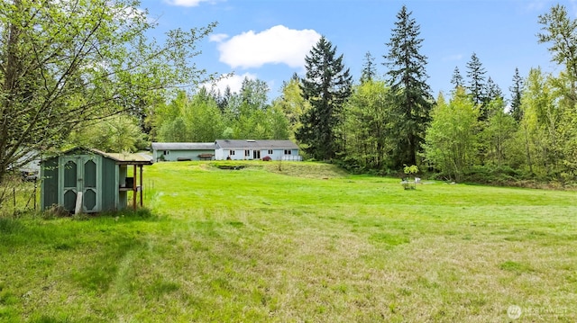 view of yard with an outdoor structure, a wooded view, and a shed