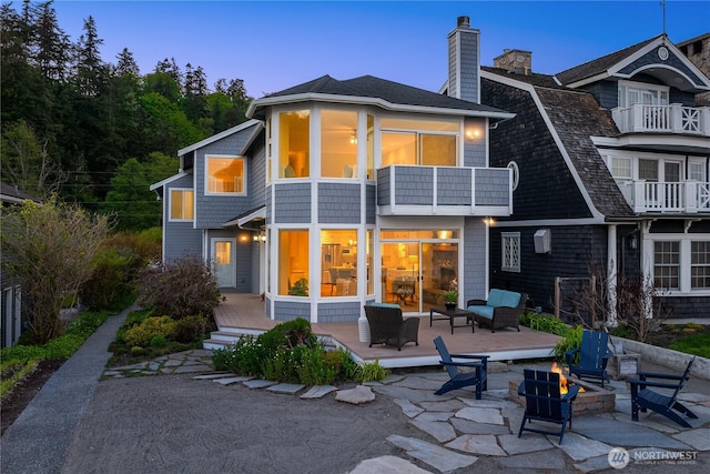 rear view of property featuring a fire pit, a balcony, a deck, a patio, and a chimney