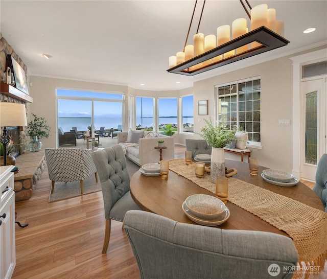 dining space featuring a large fireplace, ornamental molding, and a wealth of natural light