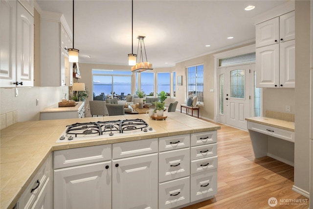 kitchen with crown molding, white cooktop, a peninsula, white cabinetry, and light wood-type flooring