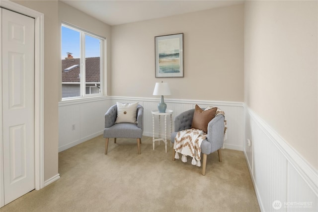 living area with a wainscoted wall and light carpet