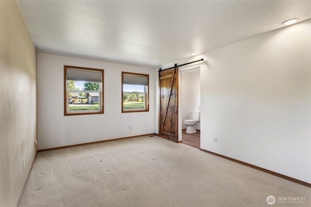 2710 Willowdale Rd, Ellensburg, WA 98926 - unfurnished bedroom featuring light carpet, a barn door, baseboards, and ensuite bathroom