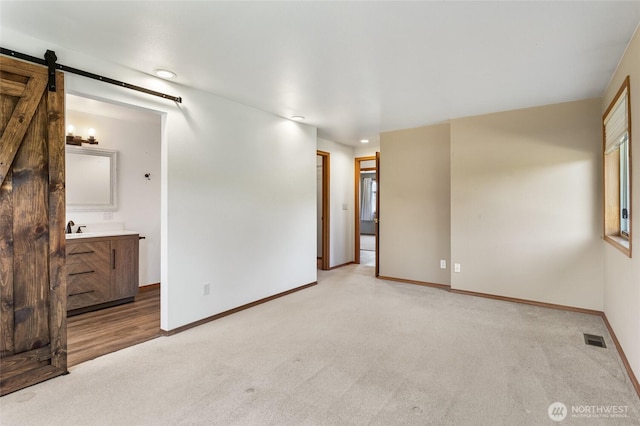 2710 Willowdale Rd, Ellensburg, WA 98926 - spare room featuring a barn door, baseboards, light carpet, a sink, and recessed lighting