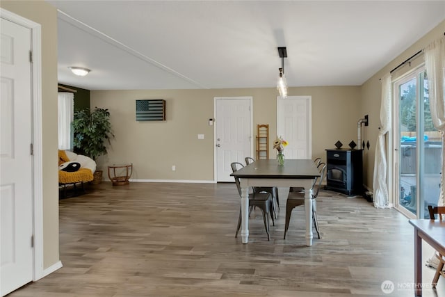 dining room with baseboards, a wood stove, and light wood-style floors
