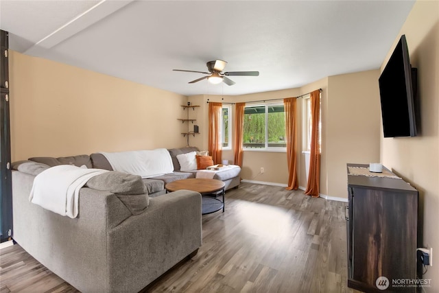living room featuring baseboards, ceiling fan, and wood finished floors