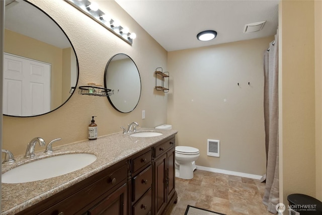 full bath with double vanity, a sink, baseboards, and toilet