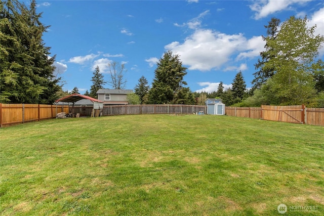 view of yard featuring an outdoor structure, a fenced backyard, and a shed