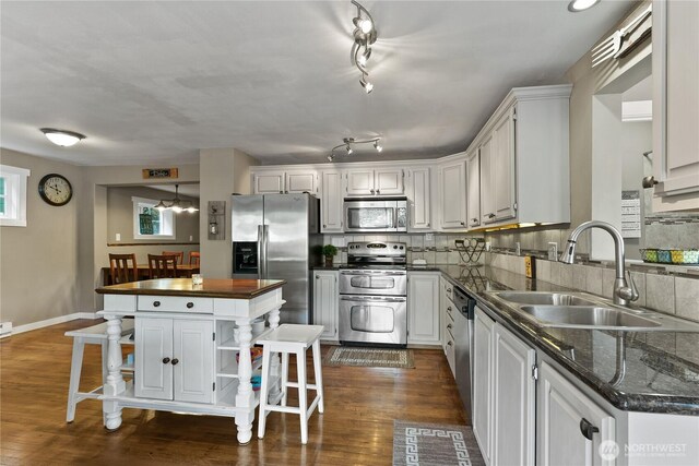 kitchen featuring open shelves, white cabinets, a sink, dark wood finished floors, and stainless steel appliances