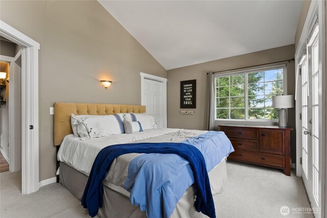 bedroom featuring baseboards, lofted ceiling, and light colored carpet