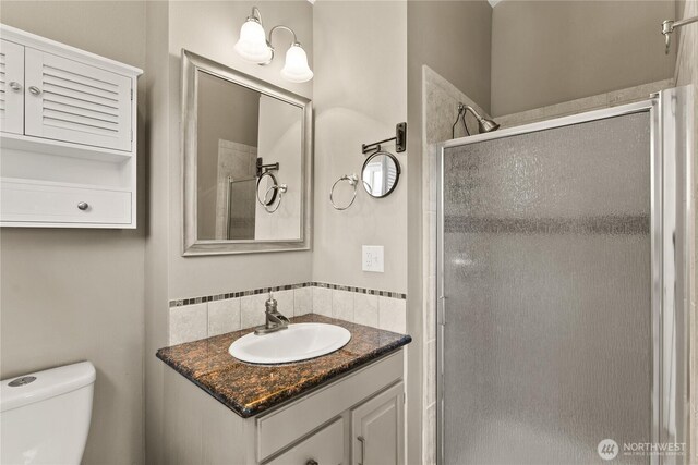 full bathroom featuring vanity, a shower stall, and toilet