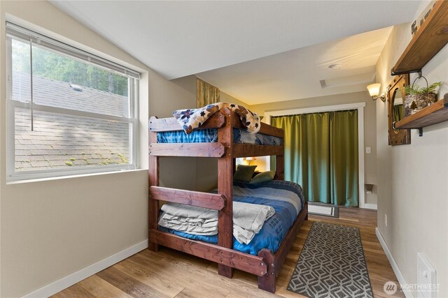 bedroom with baseboards, lofted ceiling, wood finished floors, and visible vents