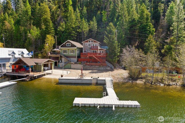 view of dock featuring a deck with water view, stairway, and a forest view