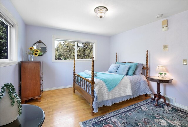 bedroom featuring multiple windows, light wood-style floors, and baseboards