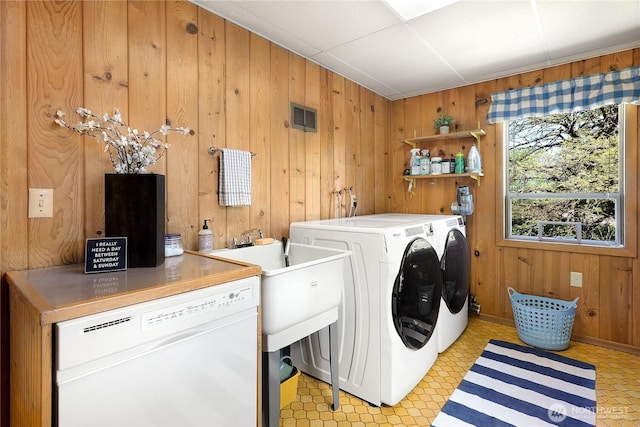 washroom featuring washer and clothes dryer and wooden walls