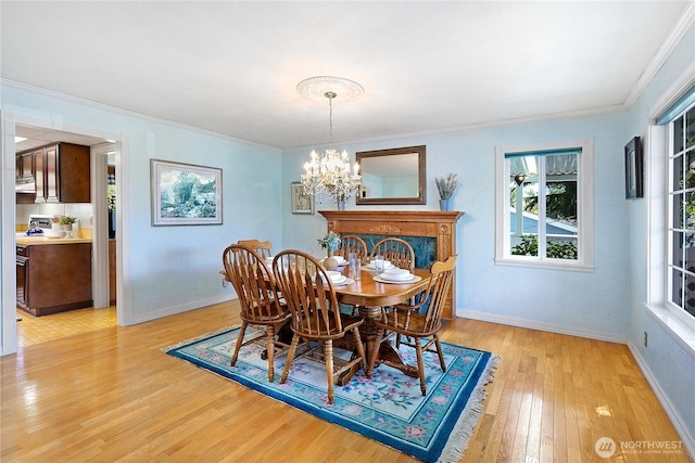 dining area featuring light wood-type flooring, a chandelier, baseboards, and crown molding