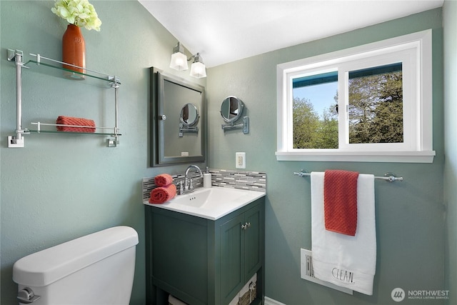 bathroom featuring vanity, toilet, and decorative backsplash