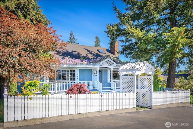 view of front facade with a porch, a chimney, and a fenced front yard