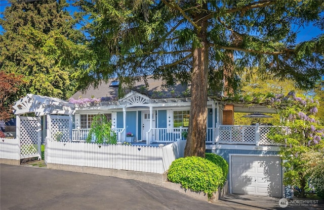 view of front of house featuring a porch, a garage, and a fenced front yard
