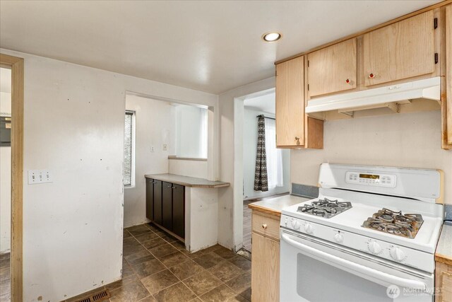 kitchen featuring light brown cabinetry, light countertops, white gas range oven, under cabinet range hood, and recessed lighting