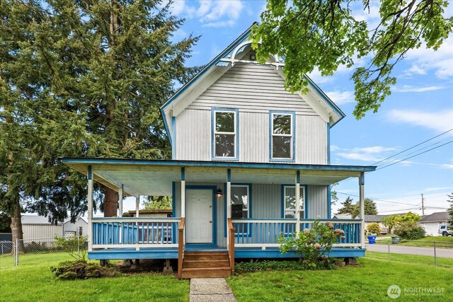 farmhouse inspired home with fence, covered porch, and a front yard