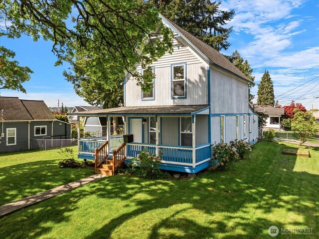 farmhouse inspired home featuring fence, covered porch, and a front lawn