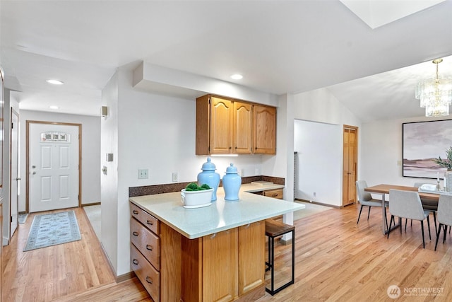 kitchen with a breakfast bar area, a peninsula, light wood-style flooring, a chandelier, and recessed lighting