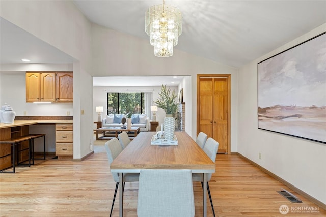 dining area with light wood finished floors, a chandelier, vaulted ceiling, and baseboards