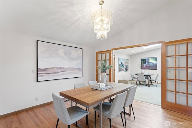 dining room with lofted ceiling, a chandelier, light wood-type flooring, and baseboards