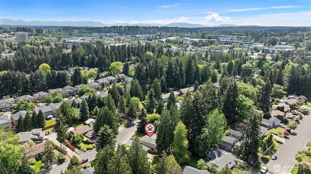 aerial view of property and surrounding area featuring mountains and a heavily wooded area