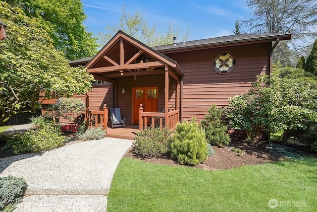 view of front of property featuring a deck, french doors, and a front lawn