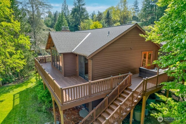 rear view of house with a yard, a deck, stairway, and roof with shingles