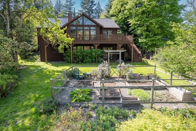 rear view of house with stairs, a wooden deck, a vegetable garden, a chimney, and a lawn