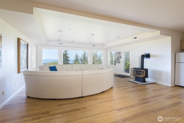 581 Harbor View Dr, Port Angeles, WA 98363 - living area featuring visible vents, a wood stove, baseboards, light wood finished floors, and a tray ceiling