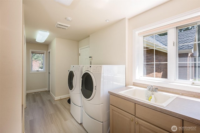 581 Harbor View Dr, Port Angeles, WA 98363 - washroom with visible vents, baseboards, washing machine and clothes dryer, a sink, and light wood-style flooring