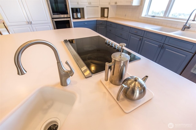 581 Harbor View Dr, Port Angeles, WA 98363 - details with stainless steel double oven, tasteful backsplash, a sink, light countertops, and black electric stovetop