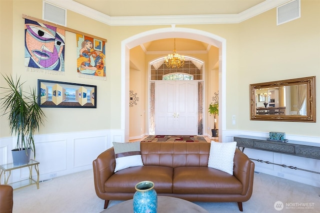 581 Harbor View Dr, Port Angeles, WA 98363 - carpeted living area with arched walkways, visible vents, ornamental molding, and a chandelier