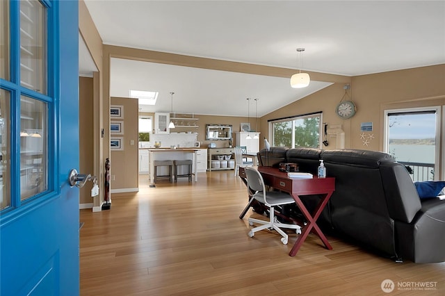 living area with light wood-type flooring, baseboards, and vaulted ceiling