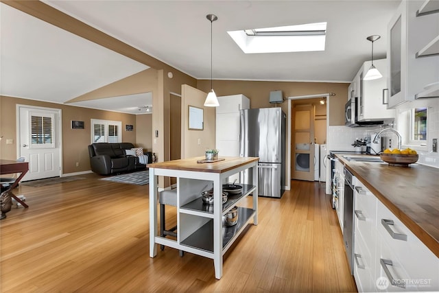 kitchen with open shelves, butcher block countertops, white cabinetry, vaulted ceiling with skylight, and stainless steel appliances