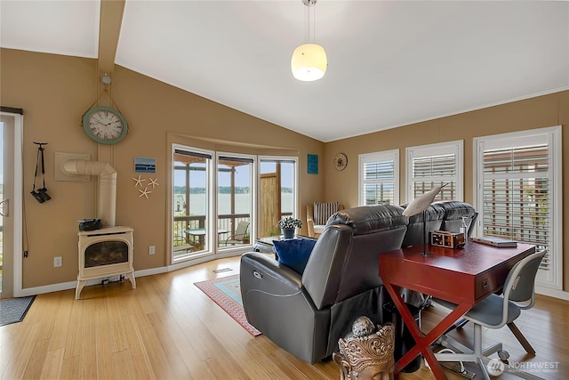 living area featuring baseboards, lofted ceiling with beams, a wood stove, and light wood-style flooring